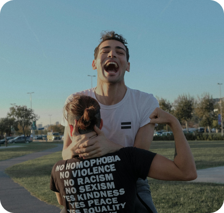 Coppia di persone LGBT che si abbracciano sorridenti durante una manifestazione.